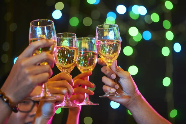 Group of people cheering with sparkling wine glasses at party
