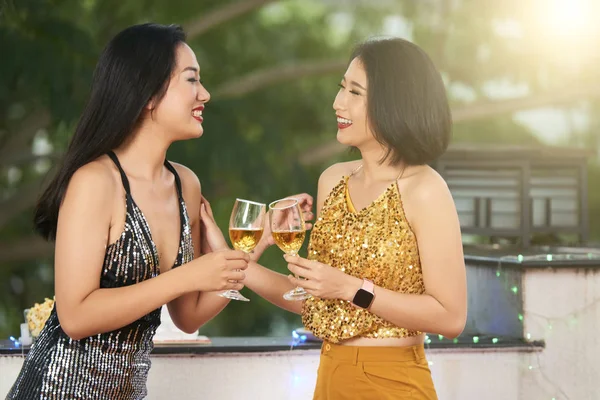 Cheerful young Asian women talking and drinking champagne at cocktail party