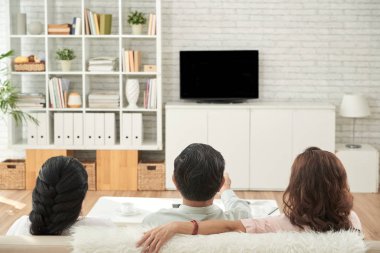 Oturma odasında büyük rahat kanepede oturan ve televizyon izlerken üst düzey insanların Arka iiew