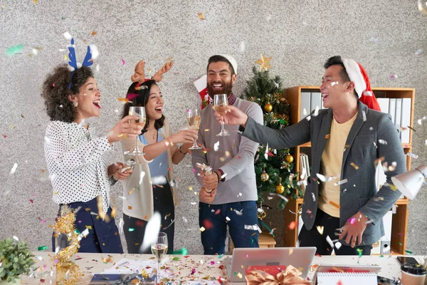 一群快乐的年轻同事在办公室享受新年庆祝活动 他们在纸屑雨下烤面包 — 图库照片