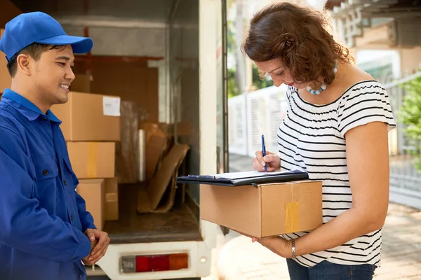 Woman Signing Document Receiving Parcel — Stock Photo, Image