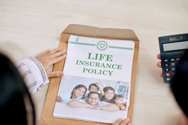 Young woman keeping hand on leaflet of life insurance policy taken out of paper packet before reading it