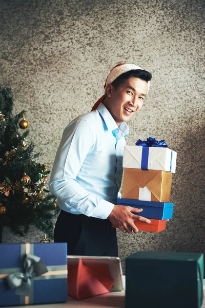 快乐的年轻亚洲企业家在圣塔帽子拿着一叠礼物 — 图库照片