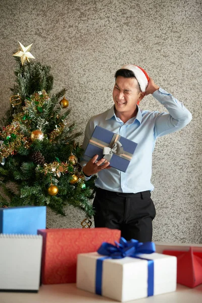 Joyful Young Asian Entrepreneur Scratching Nape Opening Boxes Secret Santa — Stock Photo, Image