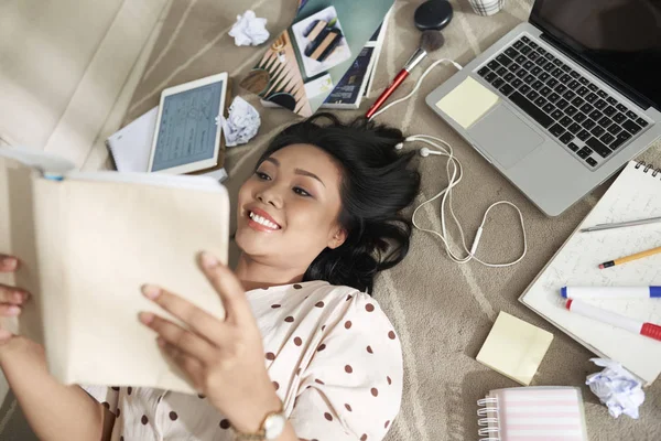 Asian Female Student Lying Floor Gadgets Notebooks Reading Book Smiling — Stock Photo, Image