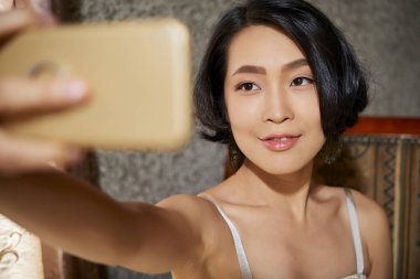 Sevimli genç Vietnamlı kadın evde selfie çekerken