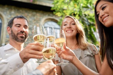 Kutlamada köpüklü şarap içen bir grup yetişkin insan