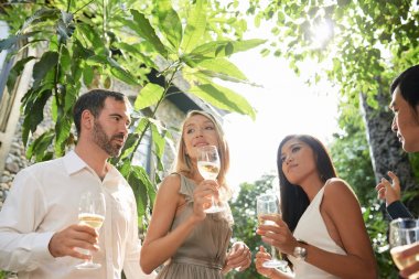 Çok ırklı parti konukları yaz günü açık havada şarap içiyor