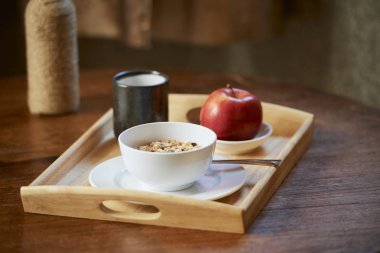 Kırmızı elma ile Tepsi, granola kase ve kahvaltı için yeşil çay fincan