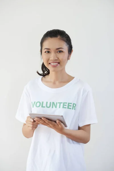 亚洲青年志愿者站在白色T恤上 手持平板电脑 在白色背景上对着相机微笑的肖像 — 图库照片