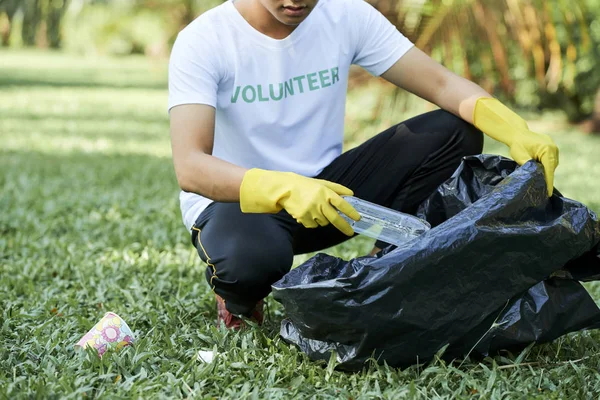 男性志愿者坐在一起 从草地上捡垃圾到户外的大黑袋的特写 — 图库照片