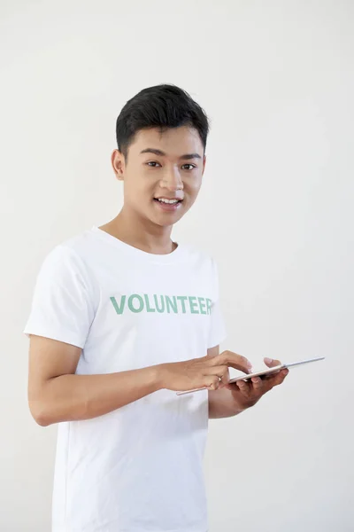 亚洲年轻男性志愿者穿着白色T恤的肖像 使用平板电脑 在白色背景的相机上微笑 — 图库照片