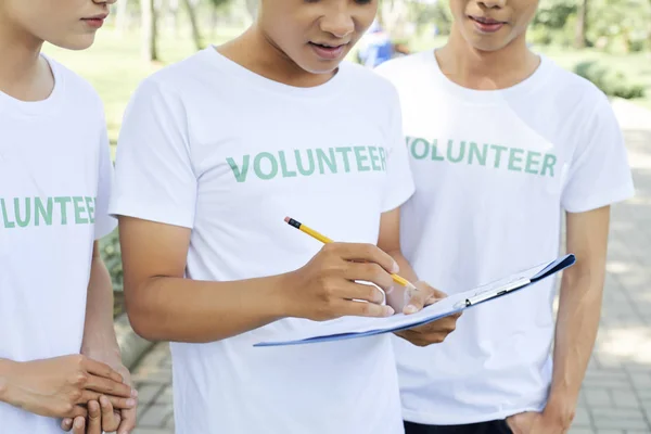 一群志愿者穿着白色T恤在户外工作时用铅笔做笔记 — 图库照片