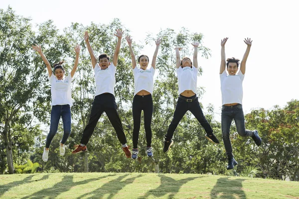 Portrait Happy Asian Teenagers White Shirts Jumping Together Arms Raised — Stock Photo, Image