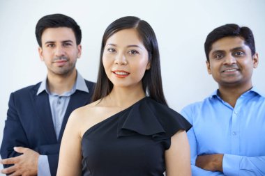 Kendine güvenen işadamları ile birlikte duran ve kameraya gülümseyen siyah elbiseli güzel Asyalı kadın portresi