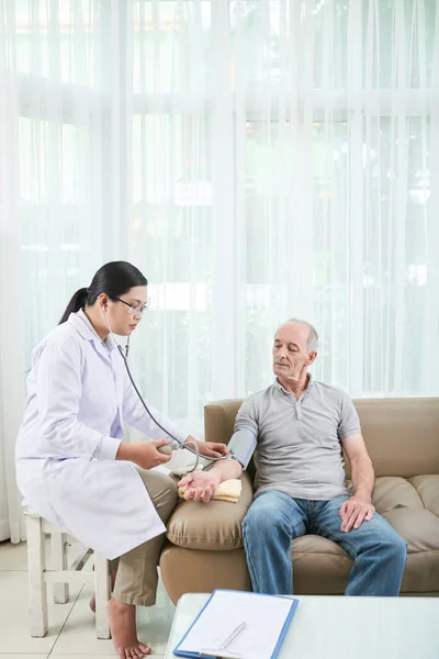 Médico Femenino Que Revisa Presión Arterial Del Paciente Senior Durante — Foto de Stock