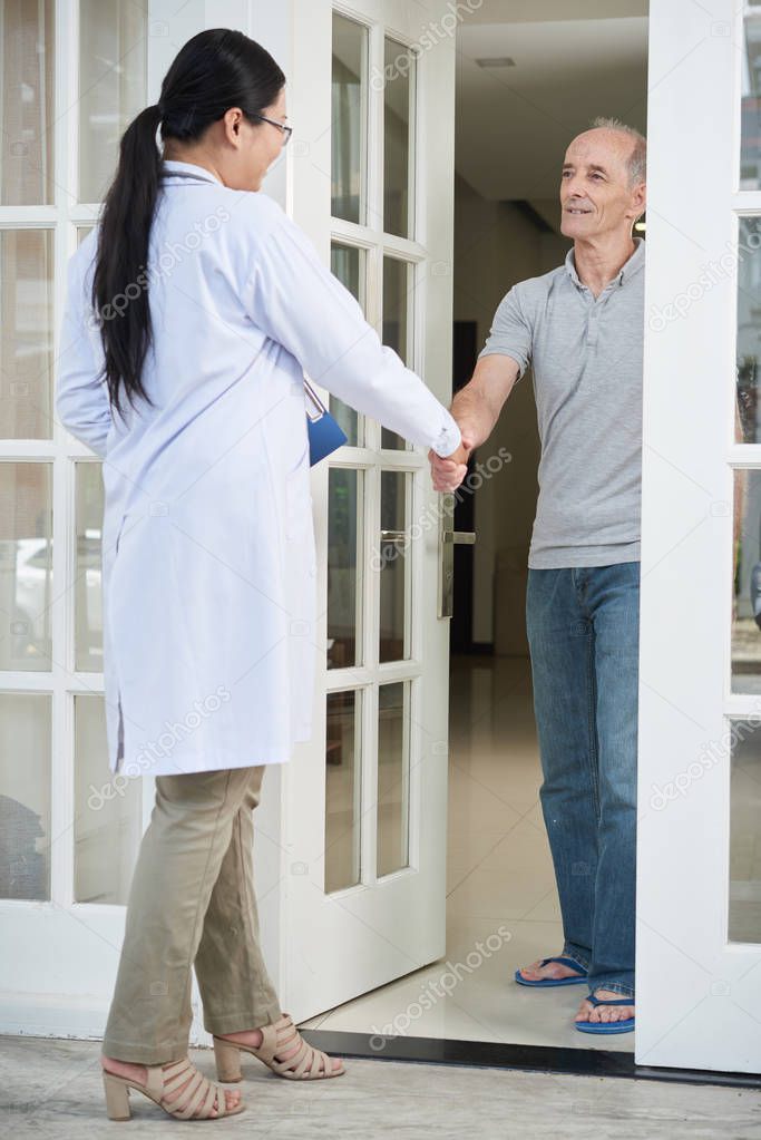Retired senior man greeting general practitioner coming to his house 