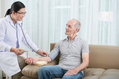 Gülümseyen kadın doktor onun üst düzey hastanın kan basıncı kontrol