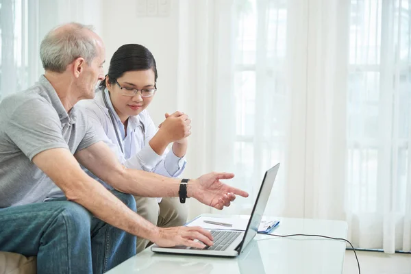 Mosolygó Nővér Senior Beteg Megvitatása Kórtörténet Laptop Képernyőjén — Stock Fotó