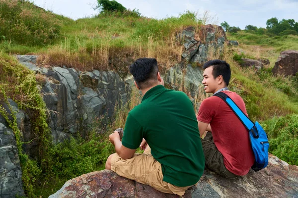 陽気な友人が紅茶を飲み 大きな岩の上に座るときハイキングについて話し合う — ストック写真