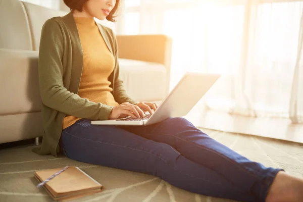 女性自由职业者坐在地板上 在阳光明媚的房间里用笔记本电脑工作 — 图库照片
