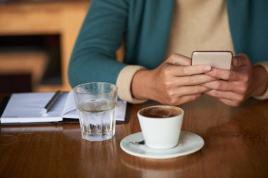 Sabah espressosu içen ve akıllı telefonda haberleri kontrol edeleyen adamın kırpılmış görüntüsü