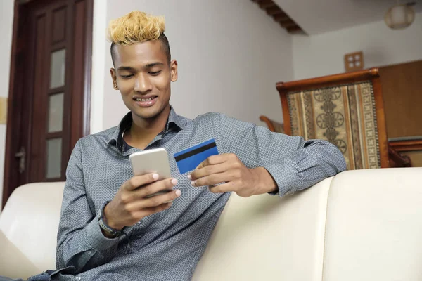 Africano Joven Sentado Sofá Escribiendo Una Información Tarjeta Crédito Teléfono — Foto de Stock