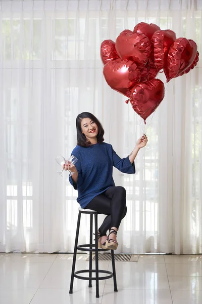 赤い風船で座って 2つのワイングラスを持っている幸せなアジアの女性の肖像画と彼女は休日を祝うつもりです — ストック写真