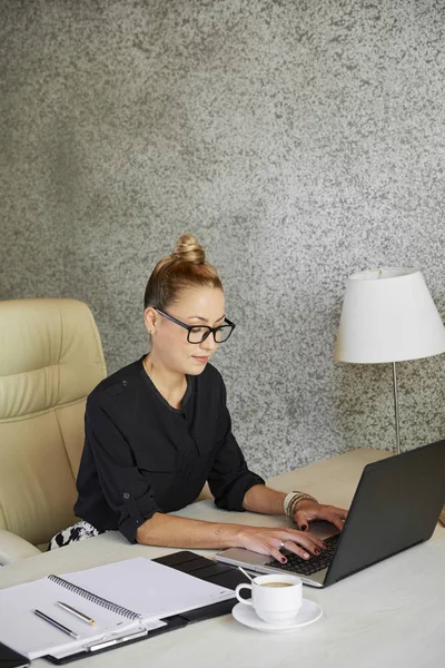 漂亮的女性业务主管在眼镜工作在笔记本电脑在她的办公桌 — 图库照片