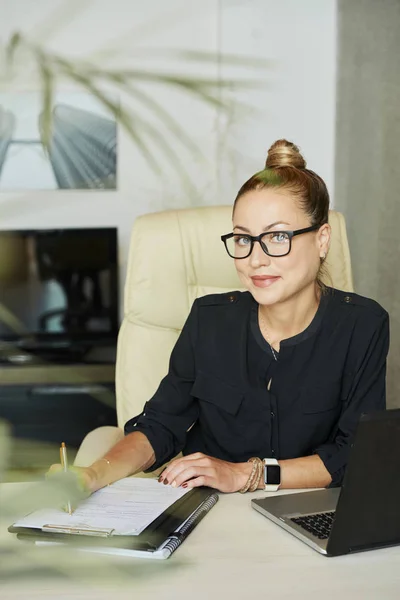开朗的女企业家坐在办公室桌旁 对着镜头微笑的肖像 — 图库照片