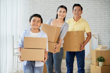 Yeni evlerinde duran birçok kutu ile Mutlu gülümseyen Asyalı aile