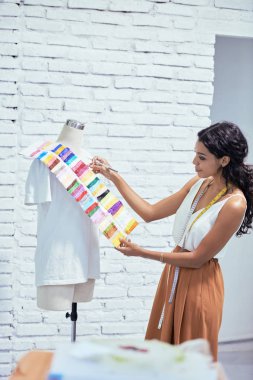 Yeni elbise için renk seçerken palet kullanarak Pretty genç kadın terzi