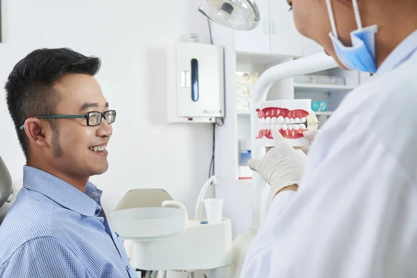 Jovem Sorridente Sentado Cadeira Dentária Ouvindo Seu Dentista Segurando Uma — Fotografia de Stock