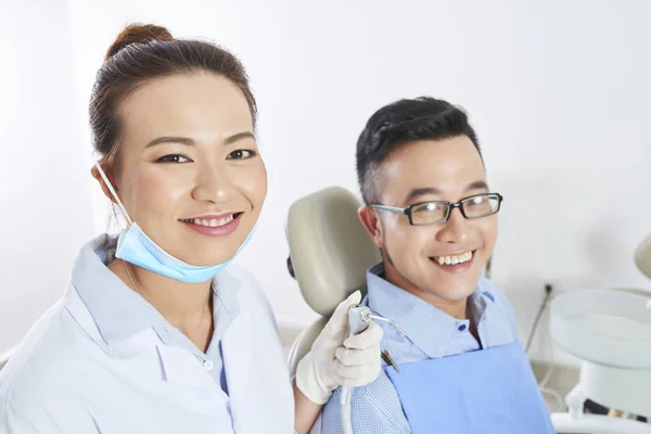 Retrato Una Joven Dentista Sonriendo Ante Cámara Mientras Trata Joven — Foto de Stock