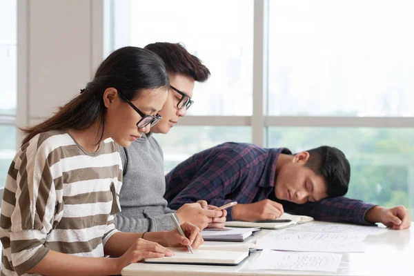 クラスメートが教科書やテキストメッセージで書くとき クラスで眠っているベトナムの大学生 — ストック写真