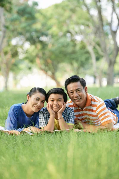 Pais Felizes Seu Filho Adolescente Deitado Grama Parque Sorrindo Para — Fotografia de Stock