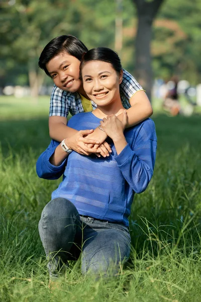 Fröhliche Vietnamesische Teenager Junge Umarmt Seine Glückliche Mutter Von Hinten — Stockfoto