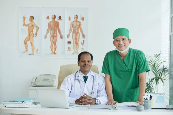 Smiling chief physician and chief surgeon in medical office