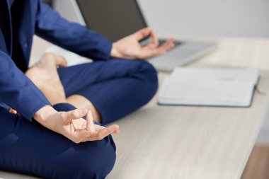 Ofis masasında lotus pozisyonunda oturan iş kadını Kırpılmış görüntü