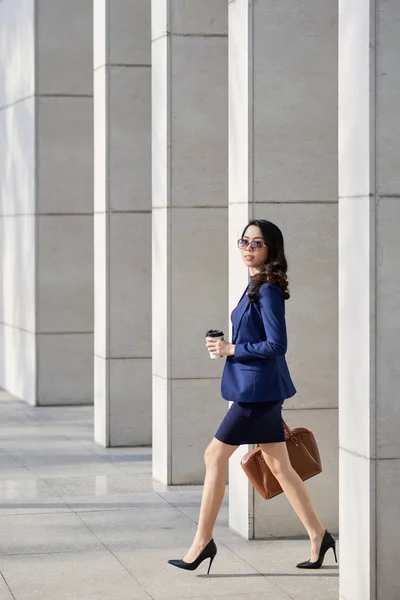 オフィスビルから出て行く短いスカートのスタイリッシュな若いビジネス女性 — ストック写真