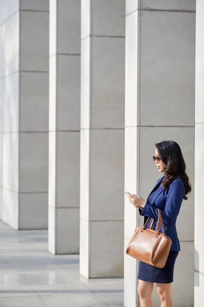 オフィスビルに立つアジアの女性起業家 携帯電話でテキストメッセージ — ストック写真