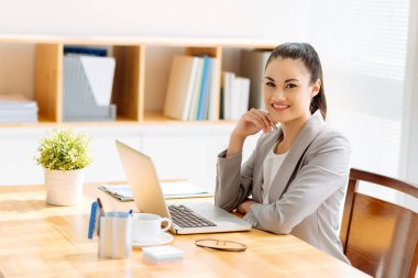Ofis masasında çalışan oldukça gülümseyen genç iş kadını portresi