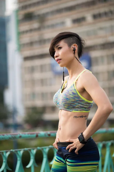 トレーニング後に屋外に立っている筋肉の体を持つかなり若いベトナムの女性 — ストック写真