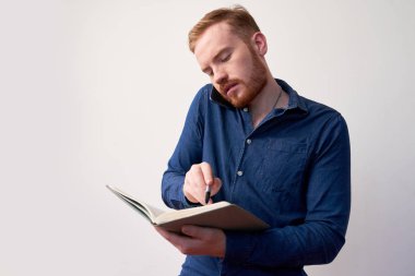 Genç girişimci telefonla arıyor ve yeni randevu almadan önce ajandasını kontrol ediyor.