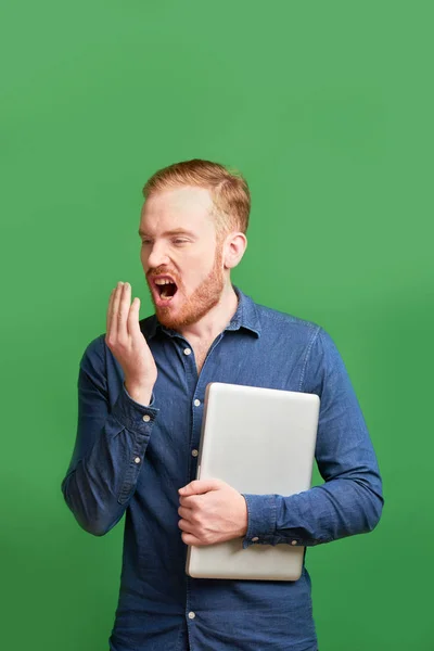 Male software engineering student exhaling on his hand to check the smell of breath