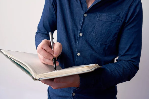 Hands of young entrepreneur writing thoughts on his planner