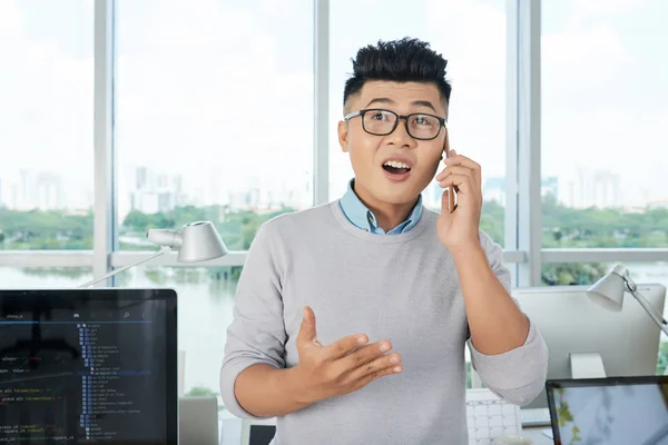 Attractive Asian Man Glass Gesturing Having Smartphone Conversation While Working — Stok Foto