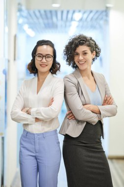 Kendine güvenen gülümseyen çok ırklı iş kadınları kolları katlanmış ve kameraya bakıyor
