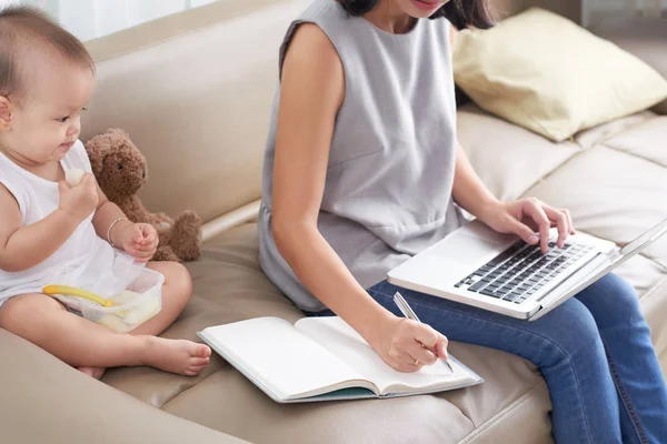 Jeune Mère Travaillant Sur Ordinateur Portable Prenant Des Notes Lorsque — Photo