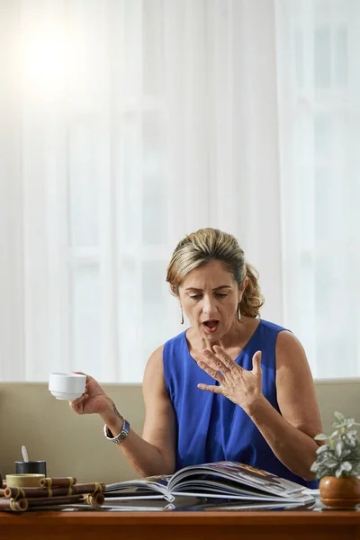 Förvånad Mogen Kvinna Tittar Tidningen Eller Fotoalbum Medan Håller Kaffekopp — Stockfoto